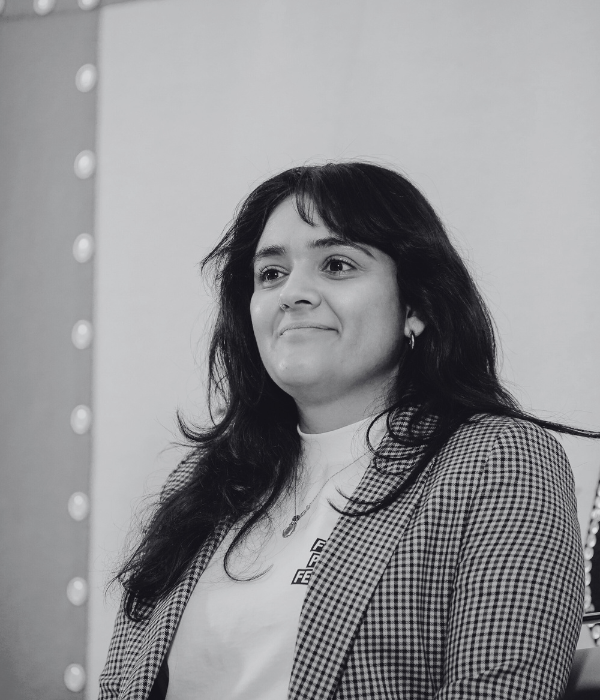 Sarah Farhatiar, CFFP Team Member and Junior Project Manager, is smiling and looking outside the frame during a conference. The picture is in black and white.