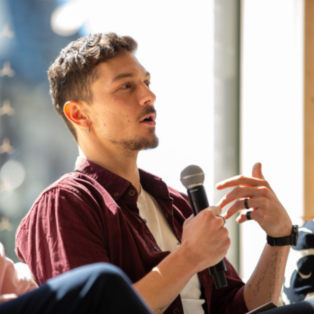 Damjan Denkovski, the Deputy Executive Director of CFFP, talking on a panel and holding a microphone.